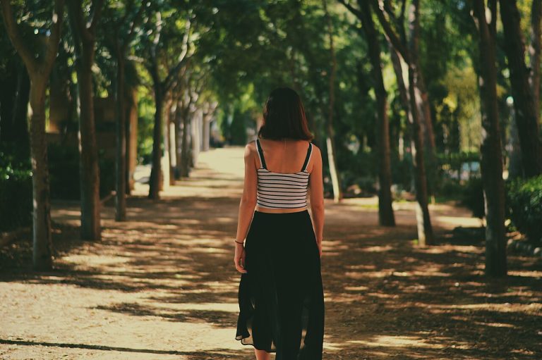 Mujer caminando por un sendero arbolado en un parque